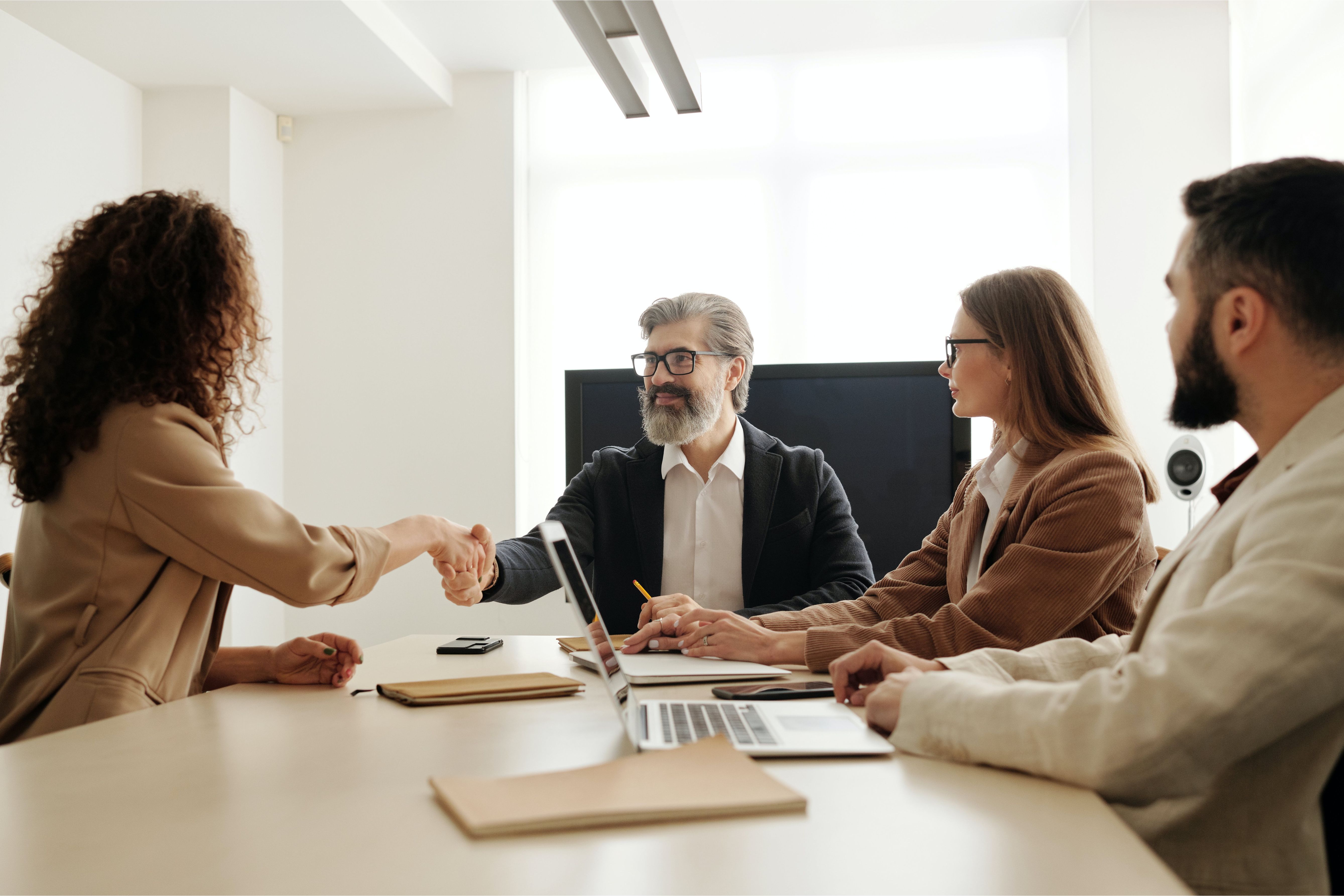 People around a table. Two people are shaking hands